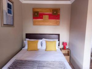 a bedroom with a bed with yellow pillows and a painting at Sally's Tranquil Airbnb in Centurion