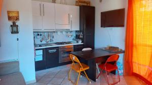 a kitchen with a black table and two orange chairs at Mare e Monti in Porto Ercole