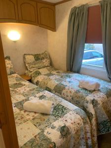 a small room with two beds and a window at Farm stay caravan on working farm in Dacre