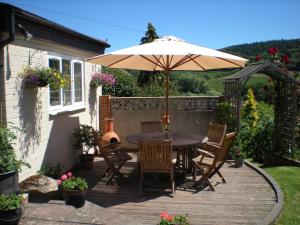a wooden deck with a table and an umbrella at Hillside Cottage in Ledbury