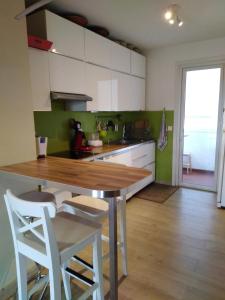 uma cozinha com uma mesa de madeira e armários brancos em Appartement confortable centre ville em LʼIsle-sur-la-Sorgue