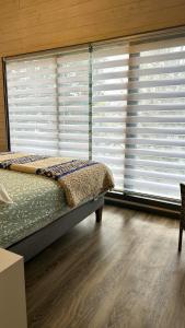 um quarto com uma cama e uma janela com persianas em Tiny House & Loft House em Panguipulli