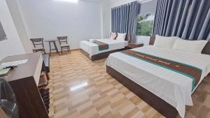 a hotel room with two beds and a desk at Family Transit Hotel in Thach Loi