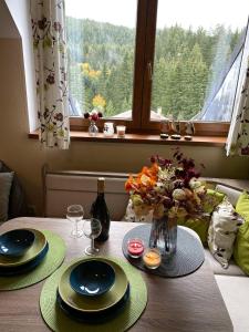 einen Tisch mit zwei Platten und eine Vase Blumen in der Unterkunft Apartman TULANIE 58 Kamzik Donovaly 2 IZBOVY Mezonet Deluxe parkovanie v podzemnej garáži ZDARMA in Donovaly