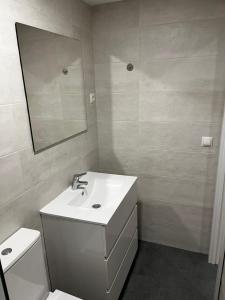 a white bathroom with a sink and a mirror at Exyca Plaza Castilla in Madrid