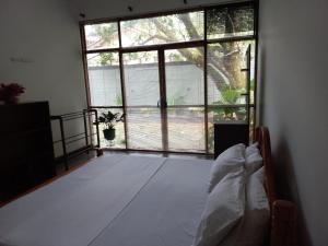 a bedroom with a bed in front of a large window at Gampaha Heritage in Gampaha