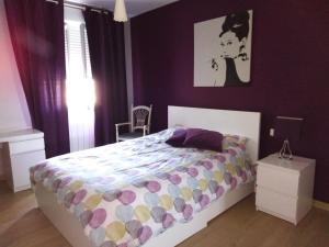 um quarto com uma cama com uma parede roxa em Appartement confortable centre ville em LʼIsle-sur-la-Sorgue