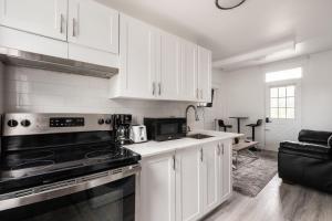 La cuisine est équipée de placards blancs et d'un four avec plaques de cuisson. dans l'établissement 2 bedroom apartment - 1005, à Montréal
