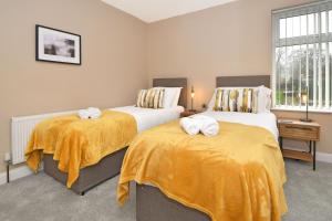 two beds in a room with yellow sheets at Mocha House by YourStays in Stoke on Trent