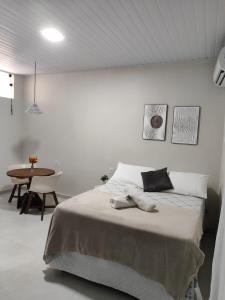 a white bedroom with a bed and a table at Casa de Mel in Itacaré