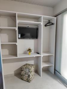 Habitación con estanterías blancas y TV. en Casa de Mel en Itacaré