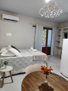 ein Schlafzimmer mit einem Bett, einem Tisch und einem Kronleuchter in der Unterkunft Casa de Mel in Itacaré