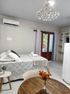 1 dormitorio con cama, mesa y lámpara de araña en Casa de Mel en Itacaré