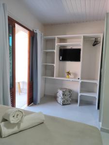 a bedroom with a bed and a tv and shelves at Casa de Mel in Itacaré