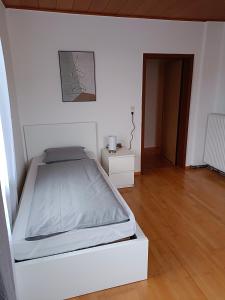 a white bedroom with a bed and a wooden floor at Historische Villa im Herzen Rankweils in Rankweil