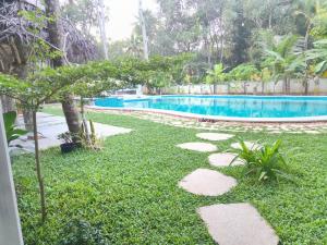 馬拉利庫蘭的住宿－Marari Beach Bungalow，一个带游泳池、草地和岩石的庭院