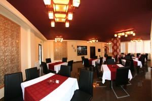 バイレ・ヘルクラネにあるPensiunea Sun-Renoの白いテーブルと赤いテーブルクロスの黒い椅子が備わるレストラン