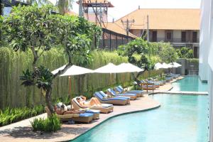 a group of people laying on lounge chairs next to a pool at Ossotel Legian in Legian