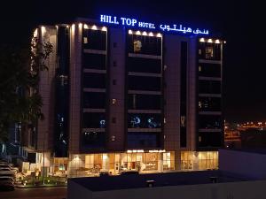 een gebouw met 's nachts een bord erop bij Hill Top Muscat in Muscat