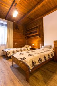 two beds in a room with wooden walls and wooden floors at Chałupa u Kaśki in Nowy Targ