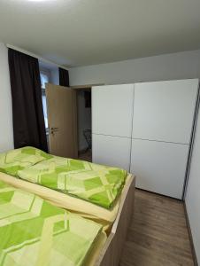 a bedroom with a green bed and a white cabinet at Ferienwohnung 1 in Schlettau