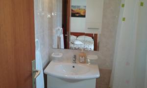 a bathroom with a white sink and a mirror at Apartments Jadrijević Brne in Primošten +49 photos