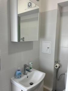 a white bathroom with a sink and a mirror at Przytulne mieszkanie w centrum Gołdap in Gołdap