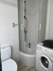 y baño con ducha y lavadora. en Przytulne mieszkanie w centrum Gołdap, en Gołdap