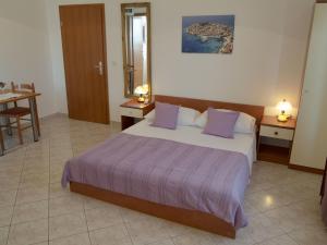 a bedroom with a large bed with purple pillows at Apartments Jadrijević Brne in Primošten