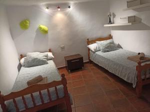 two beds in a room with two chairs and a table at Casa Rural La Yedra San Mateo in Arbejales