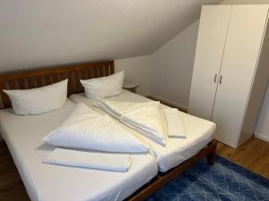 Una cama con sábanas blancas y dos toallas. en FeWo Alkapa en Hilzingen