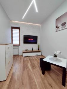 un salon avec une télévision sur un mur dans l'établissement Apartament Blisko Centrum, à Kielce
