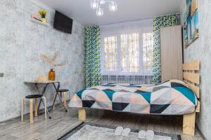 a bedroom with a bed and a table and a window at YourHouse на Си Синхая 22 близко к Меге in Almaty