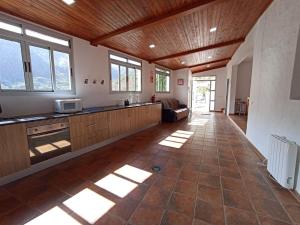 a large kitchen with wooden ceilings and windows and a floor at Casa Rural La Yedra San Mateo in Arbejales
