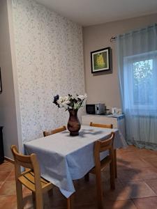 una mesa de comedor con un jarrón de flores. en Apartment Roma Tor Vergata con Giardino en Roma