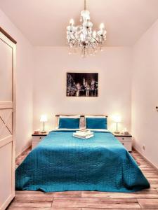 a bedroom with a blue bed with a chandelier at Z-1 Kraków Old Town O&P ApartFamily in Kraków