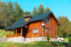 a large wooden house with a black roof at Cabana Codrii Maramuresului in Giuleşti +72 photos