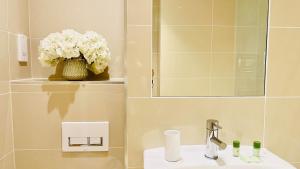 a bathroom with a sink and a vase of flowers at Urban Gem Apartment- Free parking in Enfield