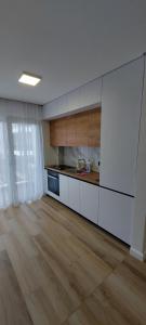 uma cozinha com armários brancos e piso em madeira em SIA Studio em Oradea