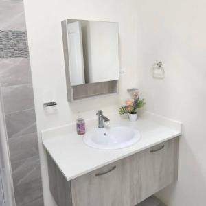 a white bathroom with a sink and a mirror at VaeTropicalParadise Free Beach & Pool Access in Discovery Bay