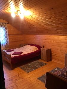 ein Schlafzimmer mit einem Bett in einer Holzhütte in der Unterkunft Карпатський Затишок in Huta