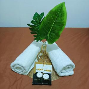 a vase with a plant on a table with towels at Chillax Condotel - Shore Residences in Manila