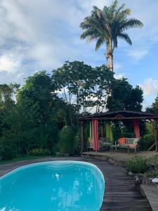 a swimming pool with a gazebo and a palm tree at Kazamwe in Petit-Bourg