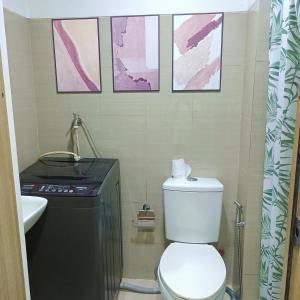 a bathroom with a toilet and a sink and some pictures at Chillax Condotel - Shore Residences in Manila