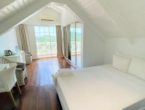 a bedroom with a large white bed and a window at Bay House Grenada in Belmont