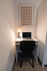 a desk with a laptop and a lamp on it at Messe Apartment Neuss Düsseldorf in Neuss