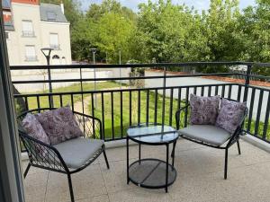 2 stoelen en een glazen tafel op een balkon bij Fantastique 2 pièces à Créteil in Créteil