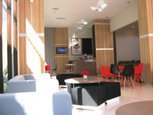 a living room with red chairs and a table at Cordela Hotel Cirebon in Cirebon