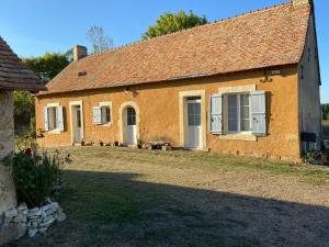 ein orangefarbenes Gebäude mit weißen Türen und einem Hof in der Unterkunft Maison de campagne - La Guenellière - Maigné - Sarthe in Maigné