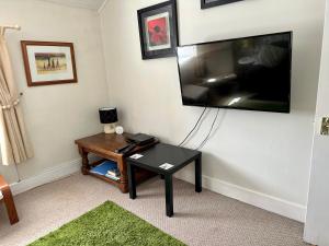 a living room with a table and a flat screen tv at The Strontian Hotel in Strontian